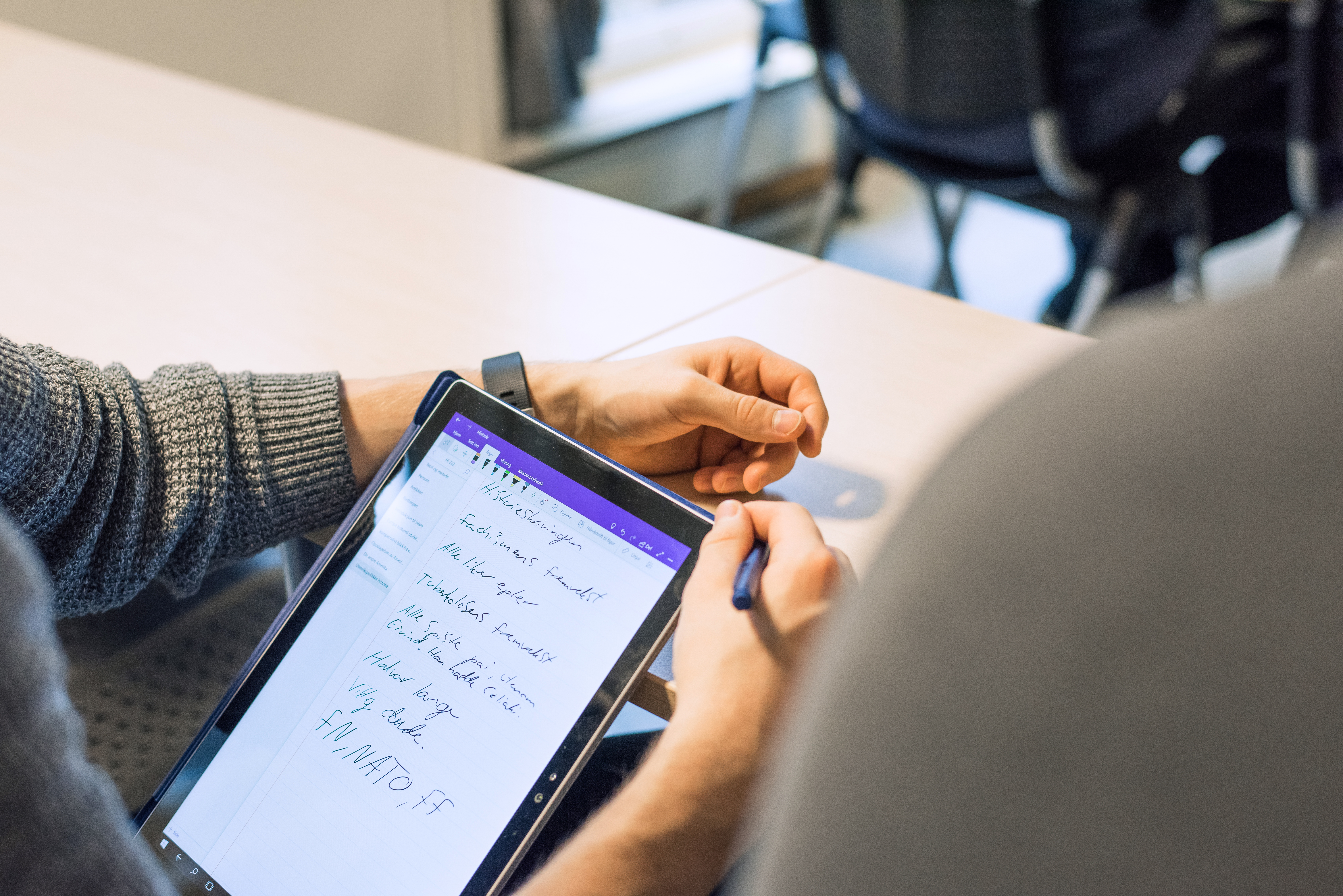 Photo of a student writing on a tablet
